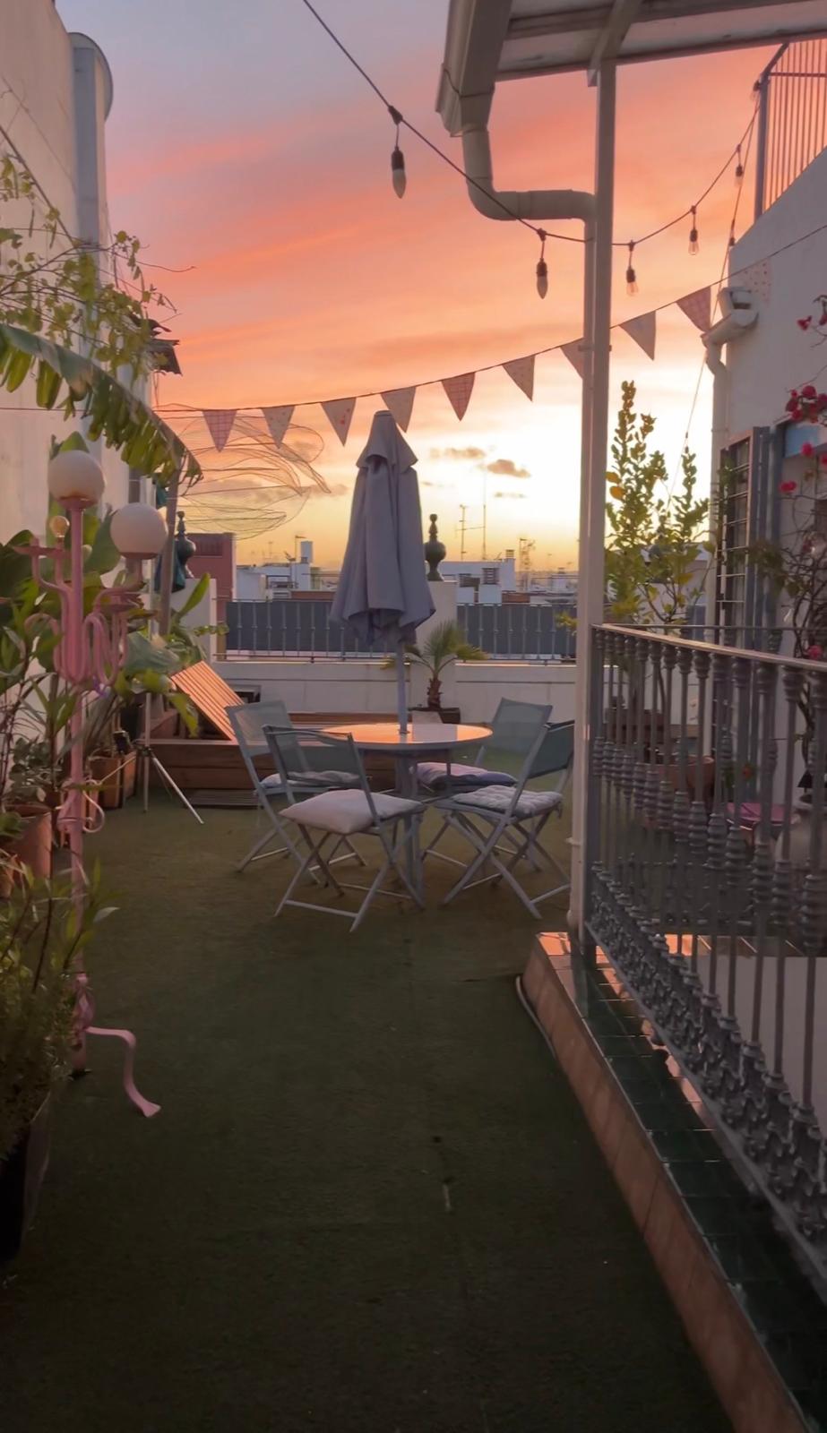 Terraza con vistas al atardecer de Sevilla, con banderines y luces de feria